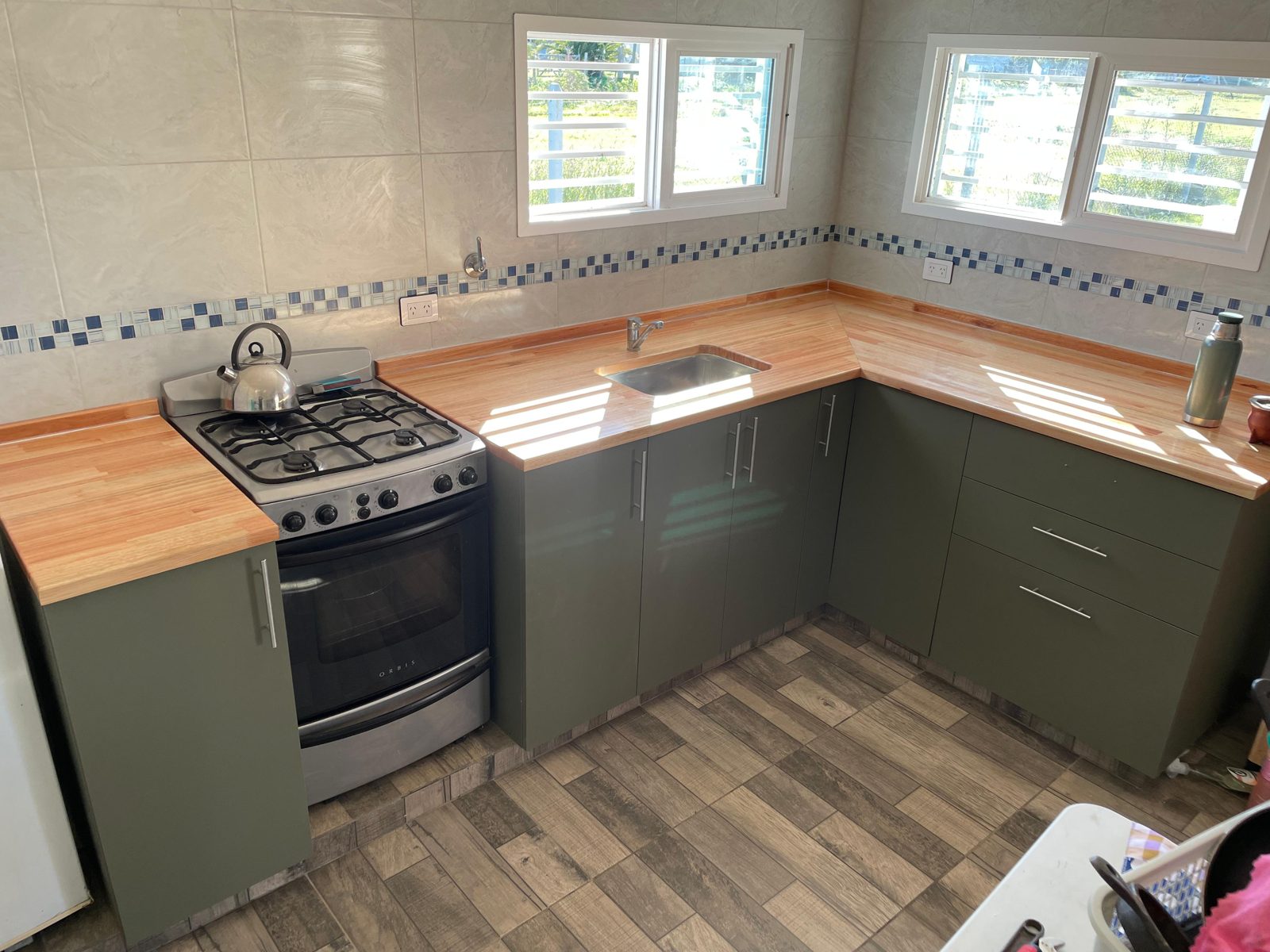 Cocina a medida con mesada de madera y muebles verdes